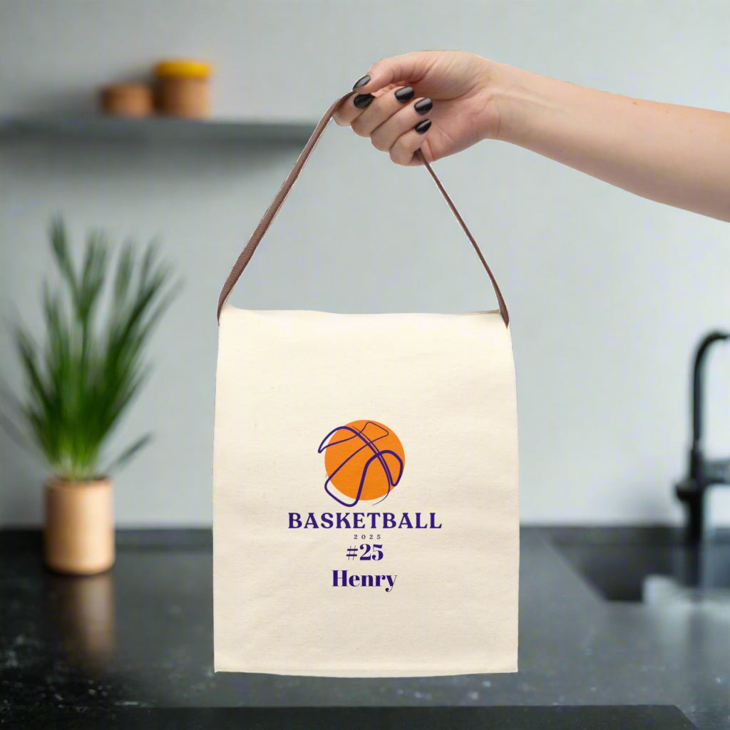 Canvas bag with basketball design and text held by a hand on a white background