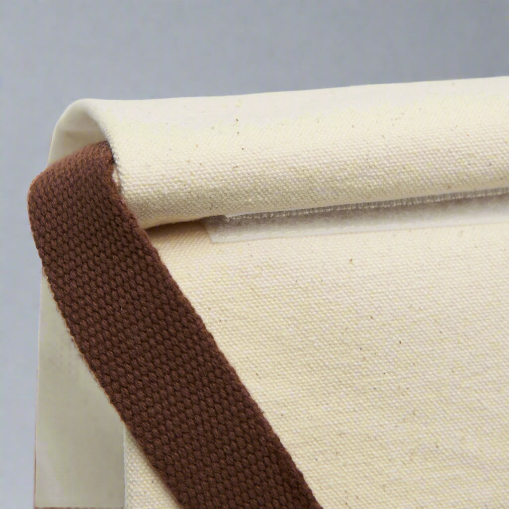 Close-up of a beige fabric roll with a brown edge on a white background