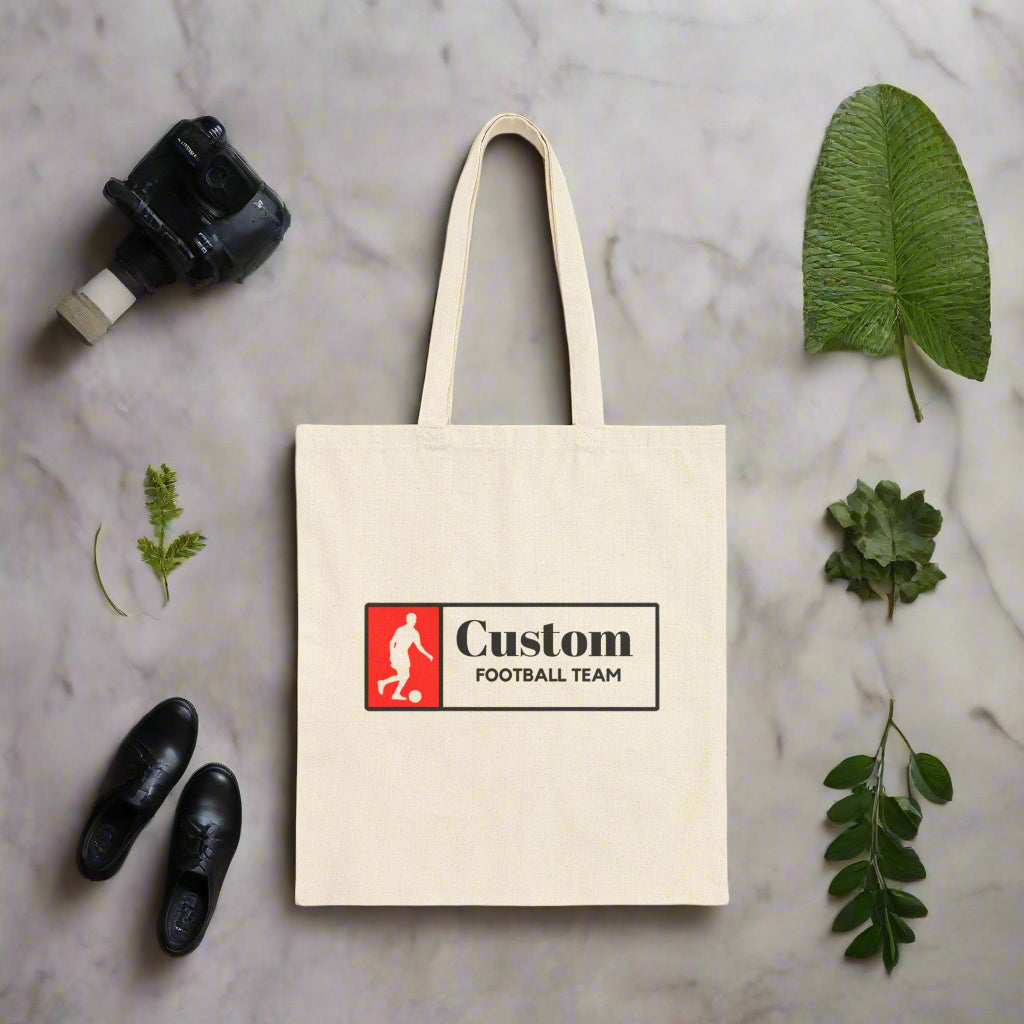 Beige tote bag with a custom football team logo on a white background